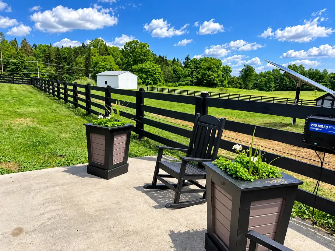 Black fence behind a patio with rocking chair and planters